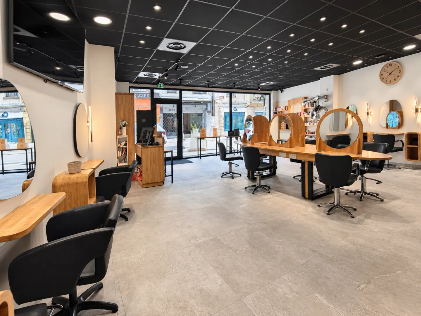 Postes de coiffage face aux miroirs ronds et vitrine sur la rue, salon de Cagnes-sur-Mer